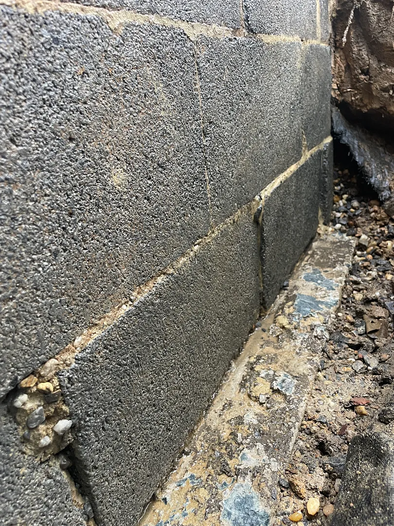 Exposed block foundation wall and base joint before exterior waterproofing in Dunn Loring