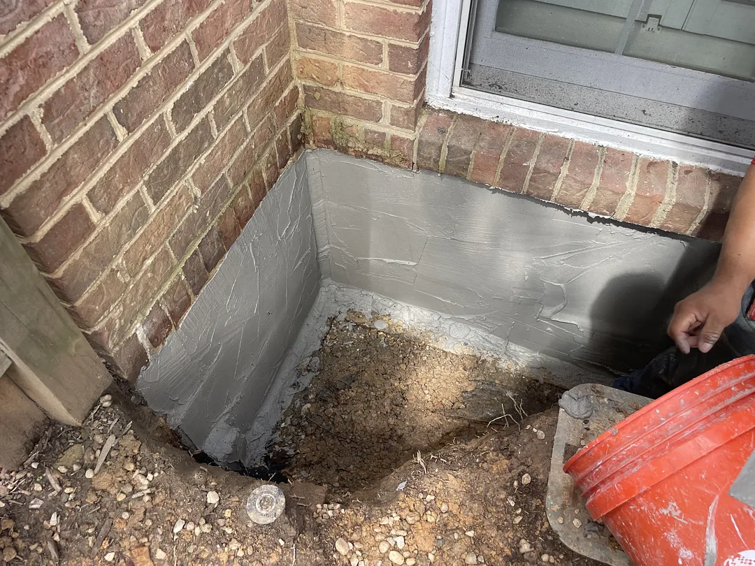 Gray cementitious waterproofing on the exterior block foundation in Dunn Loring