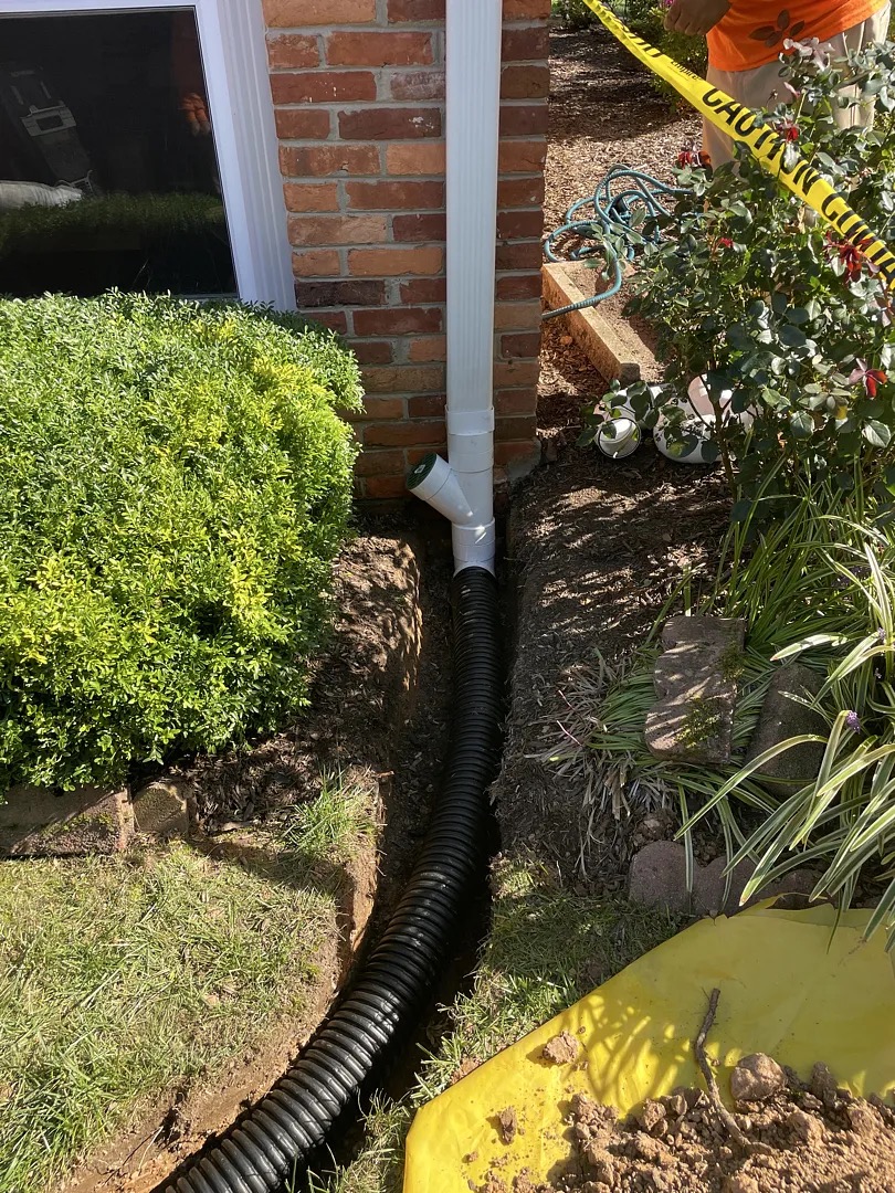 Downspout connected to a buried drainage line beside the Potomac home