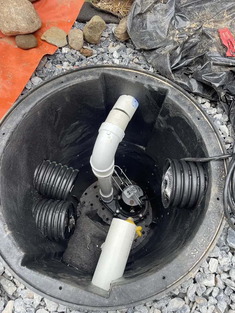 Backup sump pump inside an exterior collection basin at the basement entrance