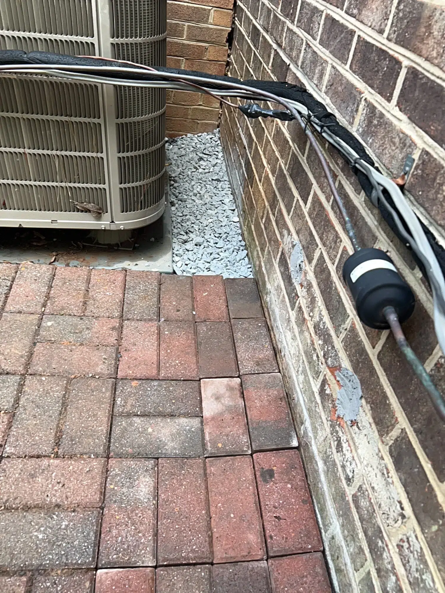 Finished gravel drainage strip beside a brick wall, pavers and air-conditioning unit in Rockville, MD